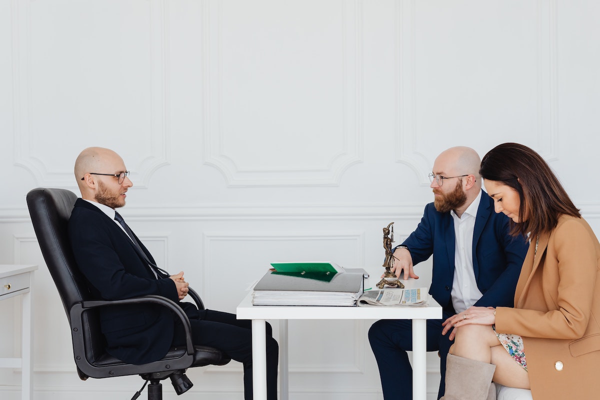 Business professionals sit at a desk with paperwork dicussing due dilligence before selling a business.